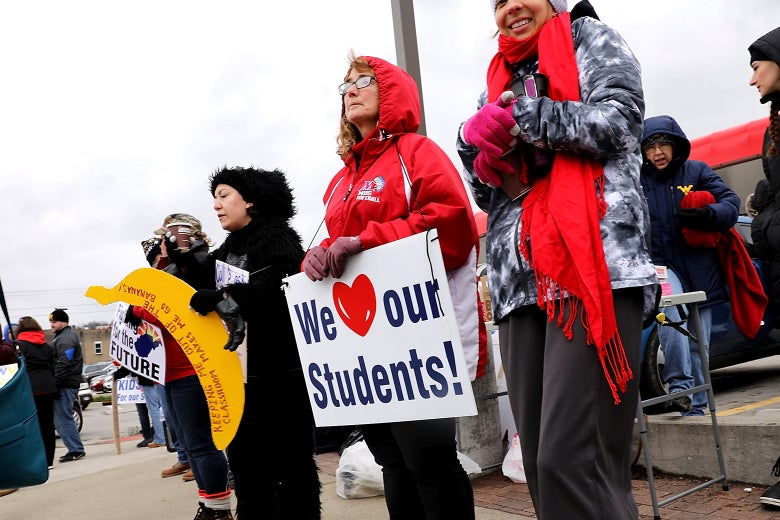 West Virginia teachers, students and supporters hold signs on a Morgantown street as they continue their strike on March 2, 2018 in Morgantown, West Virginia.